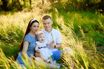 Happy family dad, mom playing in the fresh air on the field watching the beautiful emotional sunset in the backlight