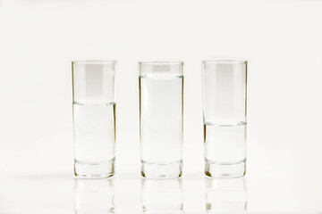 Water in three glasses - different level, isolated over a white background - three plastic bottles of water