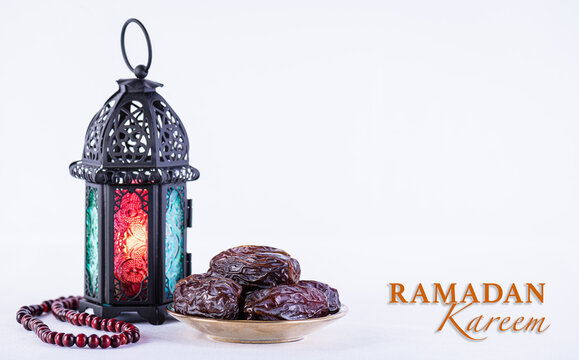 Ramadan food and drinks concept. Ramadan arabian lamp, wood rosary, and dates fruit on white background.