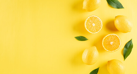 Summer composition made from oranges, lemon and green leaves on pastel yellow background. Fruit minimal concept. Flat lay, top view, copy space.