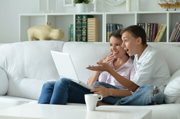 Mother and son using modern laptop at home