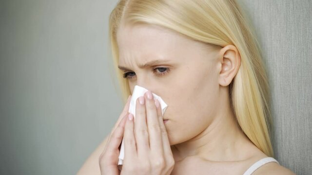 Woman blowing her nose in a living room.