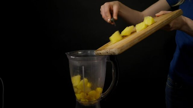 making a mango pineapple smoothie in a blender, adding pineapple to the blender