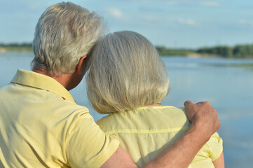 Back view of senior couple near lake during sunset at summer