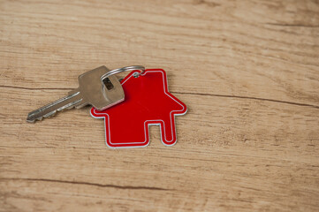 Key and house shaped keychain arrangement on wood background. Real estate, insurance concept, mortgage, buy sell house, realtor concept