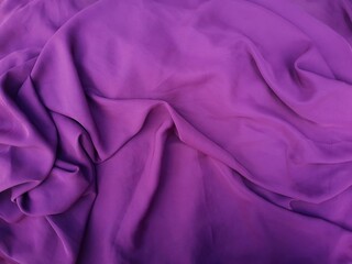 Purple textile background. Crumpled fabric with folds