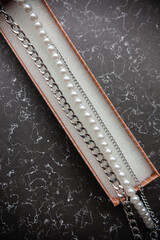 pearl jewelry and chains for girls and red tulips on a marble background