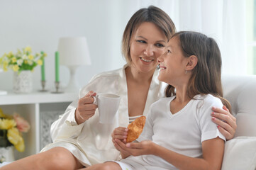 Young beautiful mother and daughter having breakfast in bed