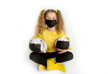 Girl in a yellow t-shirt and black mask covid19 on a white background with toys in a black covid mask