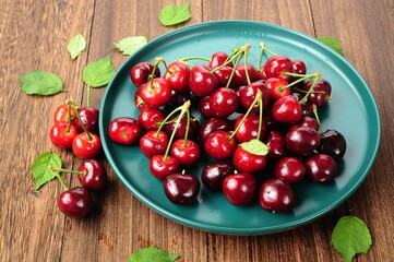 Fresh cherry fruit and leaf on wooden table.