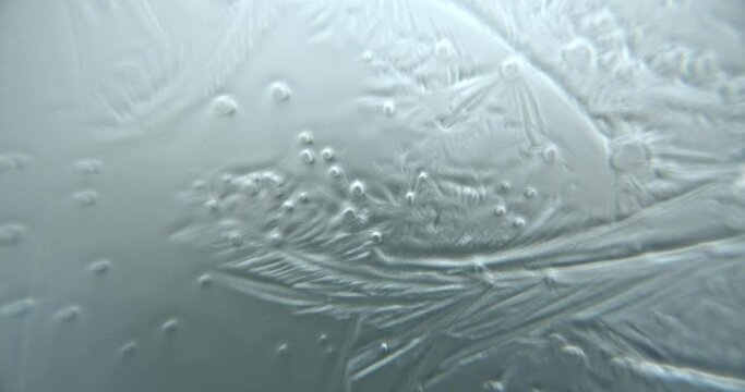 Extreme close up macroscopic shot of water crystallizing and freezing on a glass surface.
