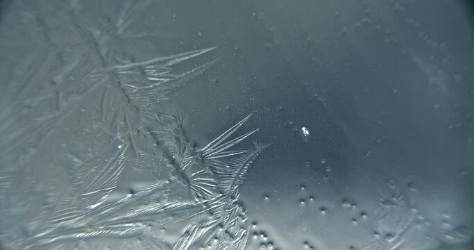 Abstract extreme close up macroscopic shot of water crystallizing and freezing on a translucent surface.