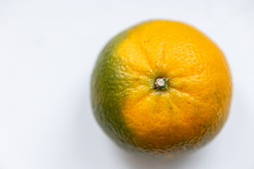One ripe orange green matte tangerine on white background. Top view. Close-up, macro. Right location