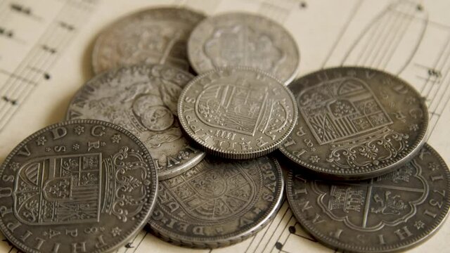 Old antique coins lie on the sheet of music close up, financial money background. Payment for creative work