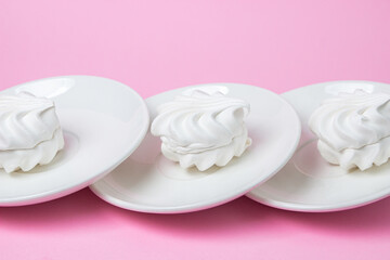 White marshmallow on a pink background. White marshmallow on a white plate. Light dessert