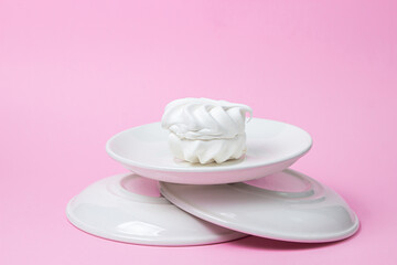 White marshmallow on a pink background. White marshmallow on a white plate. Light dessert