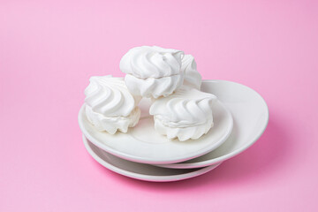 White marshmallow on a pink background. White marshmallow on a white plate. Light dessert