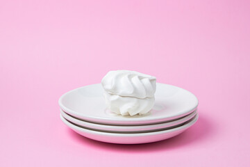 Fototapeta na wymiar White marshmallow on a pink background. White marshmallow on a white plate. Light dessert