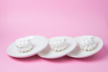 White marshmallow on a pink background. White marshmallow on a white plate. Light dessert