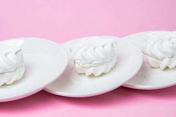 White marshmallow on a pink background. White marshmallow on a white plate. Light dessert