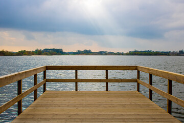 Lagoa da Vela, Portugal. View of lagoon and distant land from empty wooden pier in the morning light