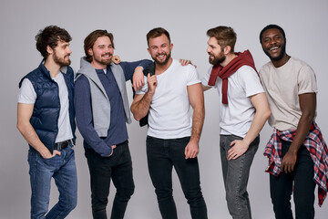 Fototapeta premium positive diverse men in casual urban style clothes posing at camera