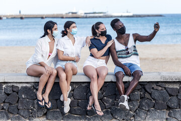 Fototapeta premium Company of multiethnic friends taking selfie on embankment