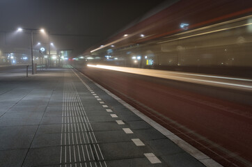 Fototapeta na wymiar Train passing an empty platform at a railroad station during a foggy evening. Groningen, Holland.