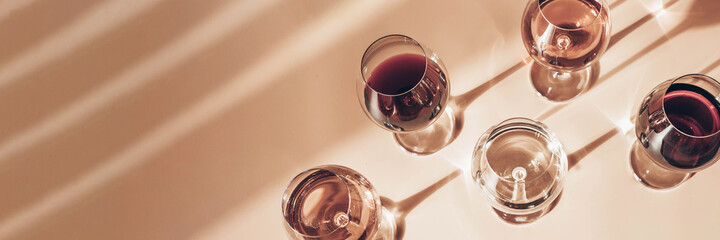 Glasses of red, rose and white wine with sunshine shadow effect. Concept of wine tasting. Flat lay,...
