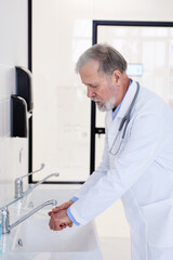 Naklejka na ściany i meble Senior Caucasian Doctor washing Hands Before Operation