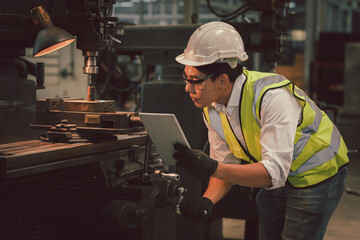 Industry engineer wearing safety uniform control operating lathe grinding machine working in industry factory.