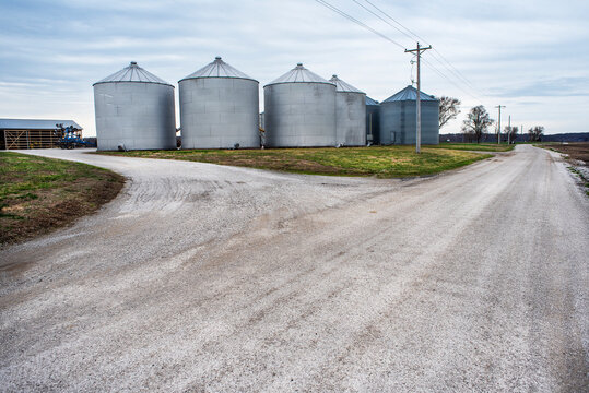 Large grain storage bins on farm next to gravel country road in rural America. farming, farmers, food, crops, storage, silos, silo, corn, grain, soybean, containers, store, dry