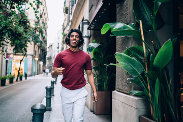 Cheerful man with headphones walking along street