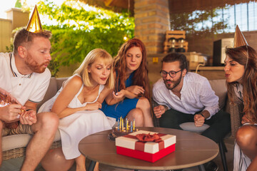 Friends blowing candles from a birthday cake