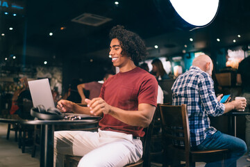 Cheerful male blogger watching streams video browsed on modern laptop enjoying leisure in coffee shop, happy millennial user working remotely reading received email with freelance web project