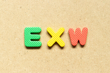 Foam alphabet letter in word EXW (abbreviation of Ex works)  on wood background