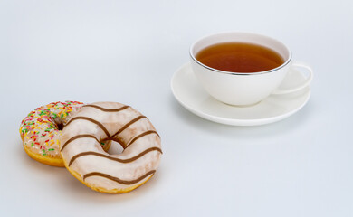 sweet donuts and a cup of tea on a white background. selective focus.