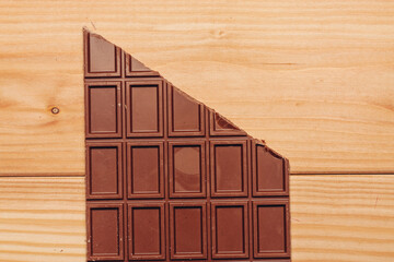 brown chocolate bar cut diagonally on wooden background