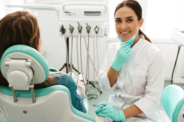 European mid dentist woman smiling while working with patient
