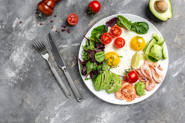 Ketogenic breakfast. Keto low carb salmon, boiled shrimps, prawns, fried eggs, fresh salad, tomatoes, cucumbers and avocado. top view. Low carb diet concept. high fat diet
