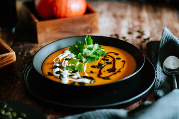 Vegetarian, homemade pumpkin cream soup in a bowl on wooden table. 