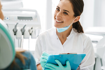 European mid dentist woman smiling while working with patient