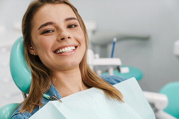 European young woman smiling while sitting in medical chair