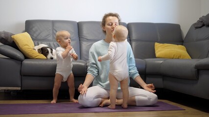 A mother trying to focus and practice yoga while her twin babies keep bothering her. Mental health during the lockdown 