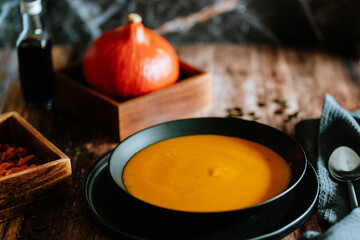 Vegetarian, homemade pumpkin cream soup in a bowl on wooden table. 