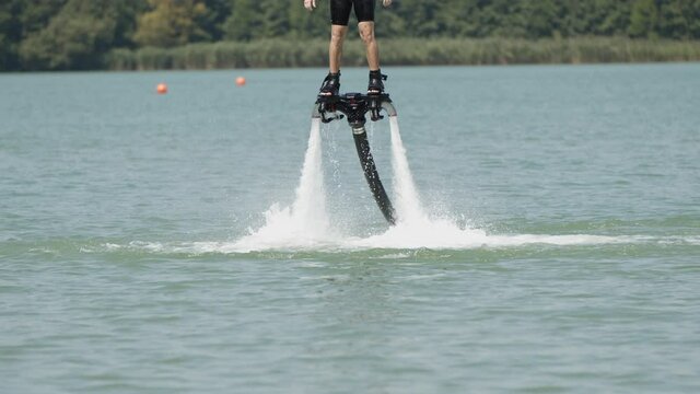Medium slow motion shot of flyboarder flying over natural lake in summer. Holiday trip in Czech,Naklo.
