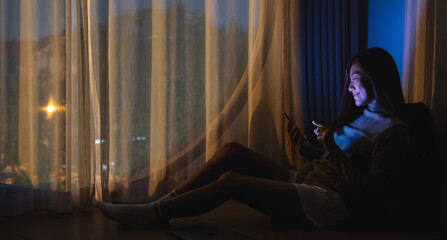 A young woman using mobile phone with bright light screen in the late night at home