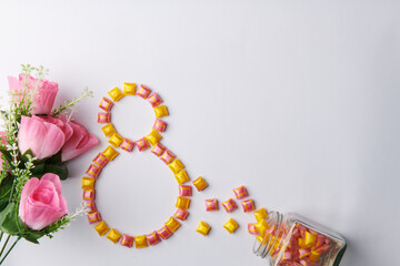 a bouquet of roses on a white background with bright candies from a jar 