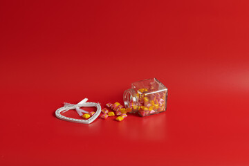 the jar lies on a red background with sweets with a heart
