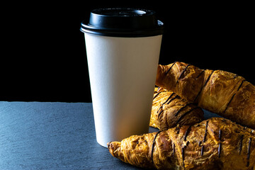 Croissant texture. French breakfast croissants, fresh pastry bread with paper coffee cup in bakery on dark stone background. Bread bakery products cafe concept.